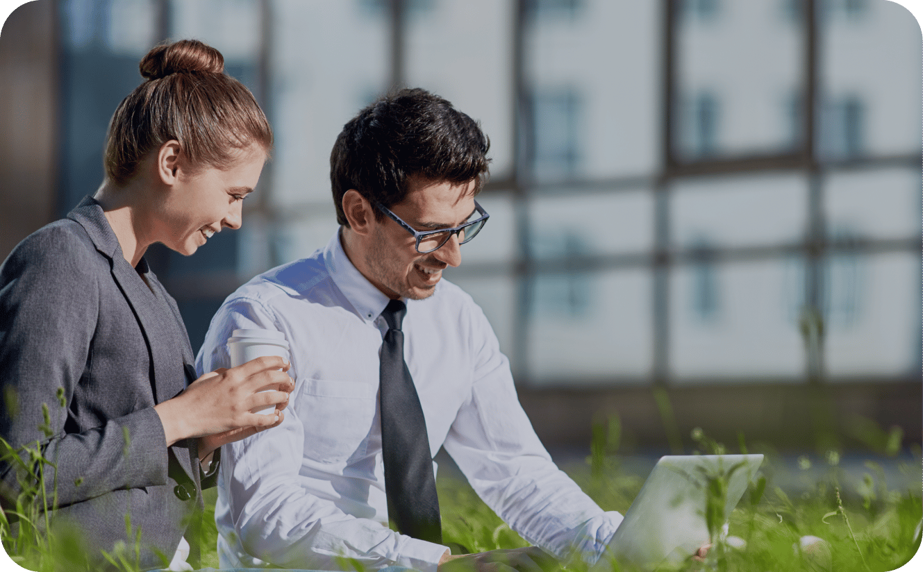 Two colleagues collaborating outdoors with laptop