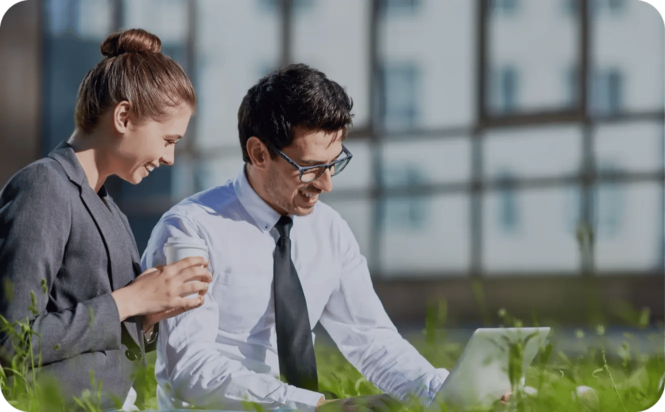 Two colleagues collaborating outdoors with laptop